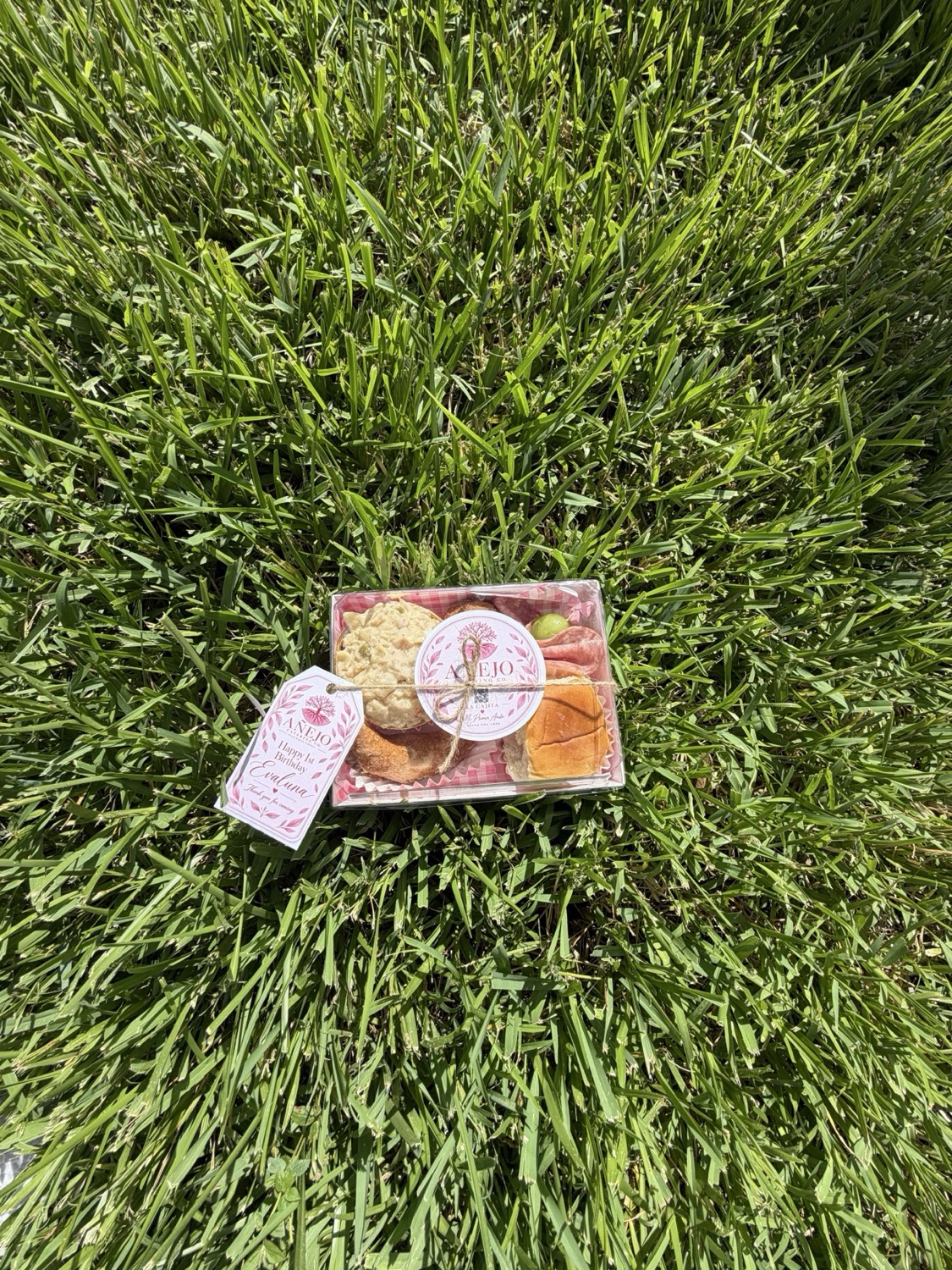 Pink first-birthday Cajita displayed outdoors